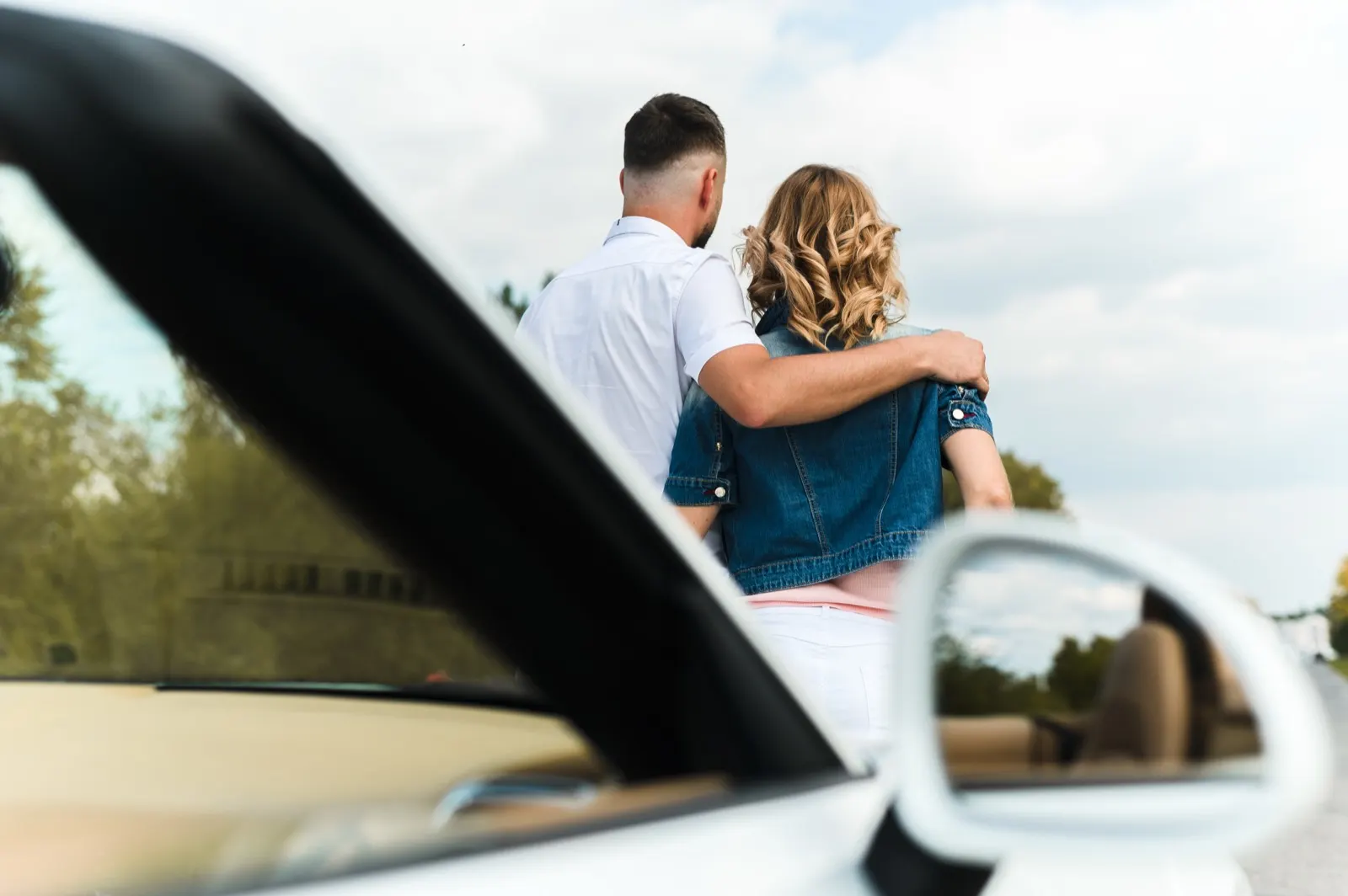 Casal em um carro conversível, celebrando a conquista do veículo